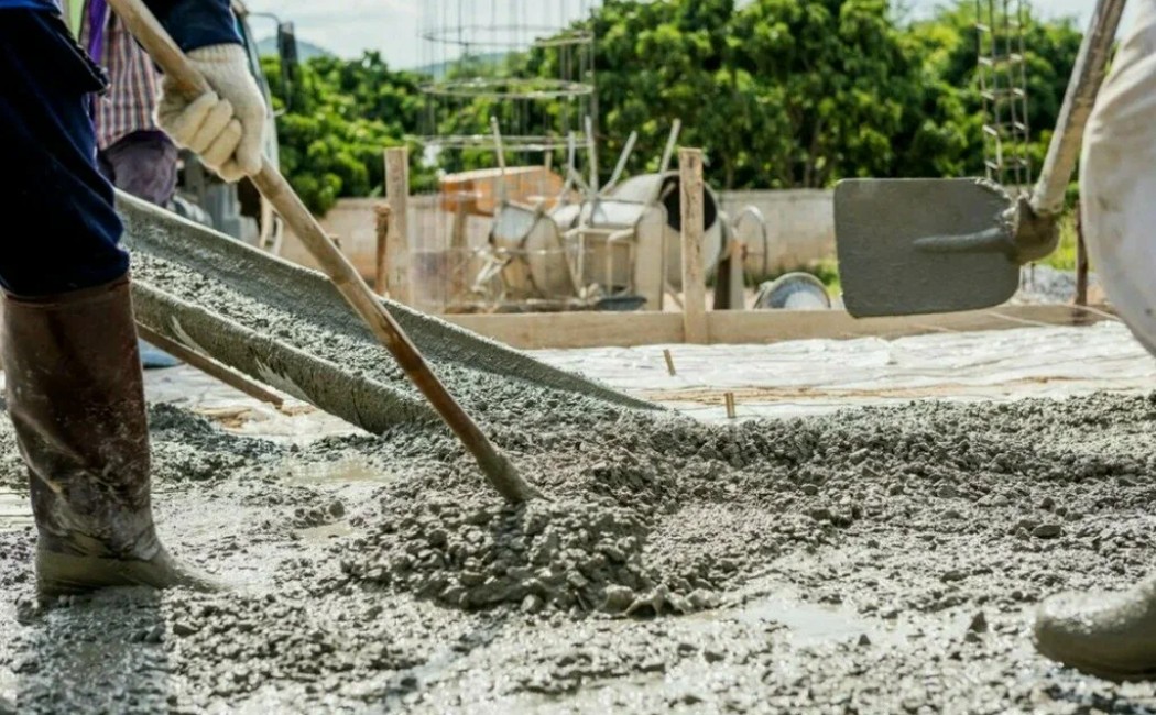 Workers are leveling and spreading freshly poured concrete at a construction site, showcasing skilled craftsmanship in professional concrete work.