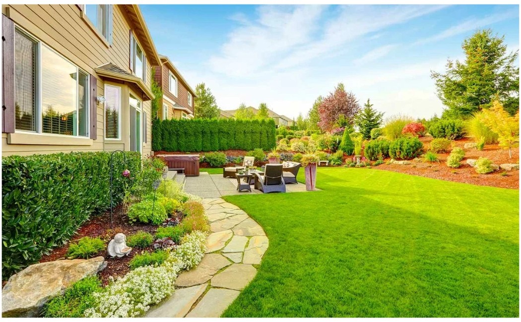 The image showcases a beautifully designed garden with lush greenery, neatly trimmed shrubs, and a well-maintained patio, exemplifying professional landscaping at its finest.