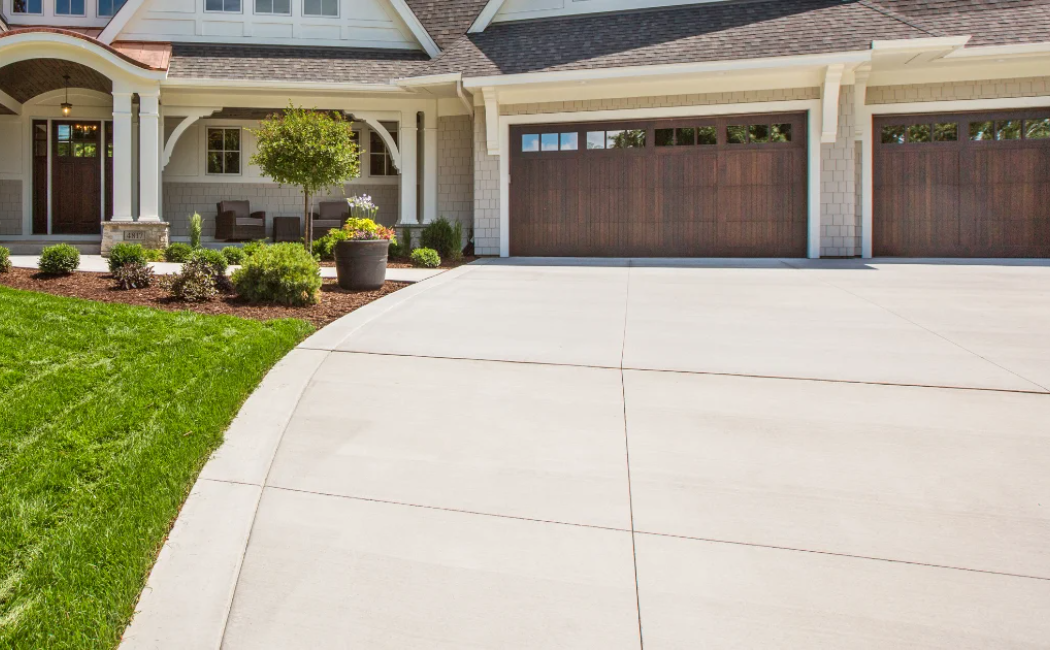 This image features a smooth, professionally installed concrete driveway with a well-manicured lawn, showcasing the quality of concrete driveway services.