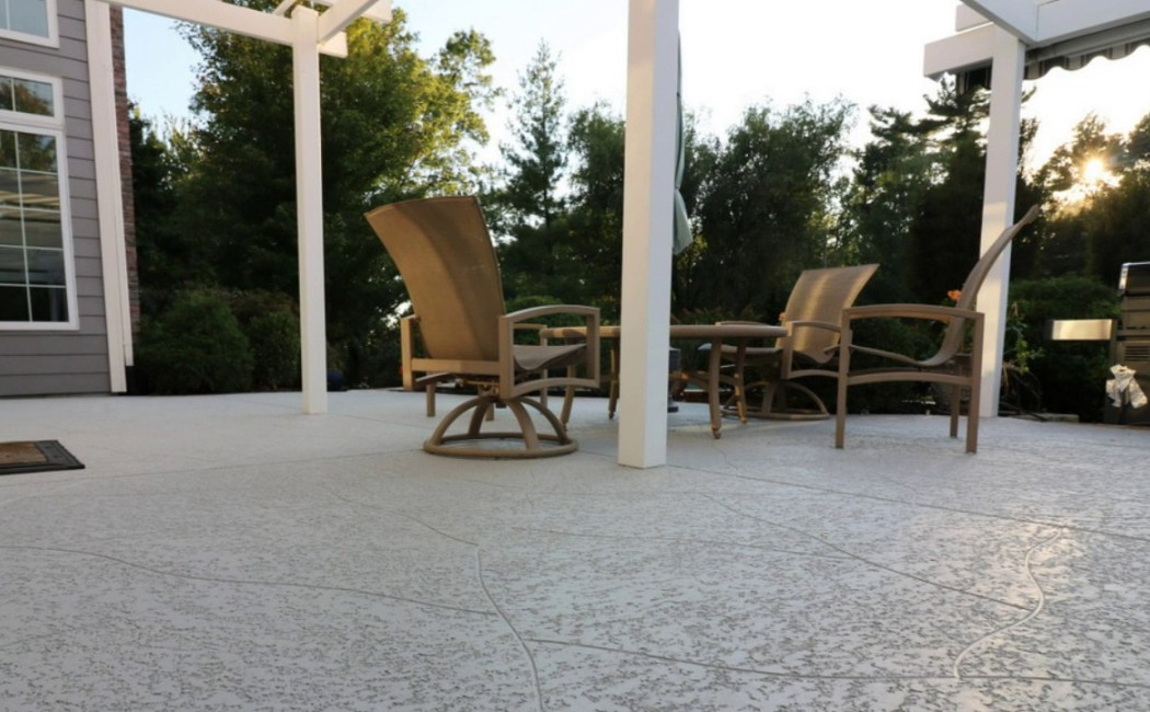 Spacious outdoor seating area with a textured concrete patio under a pergola, highlighting expert Concrete Patios Services for durable and stylish outdoor living.