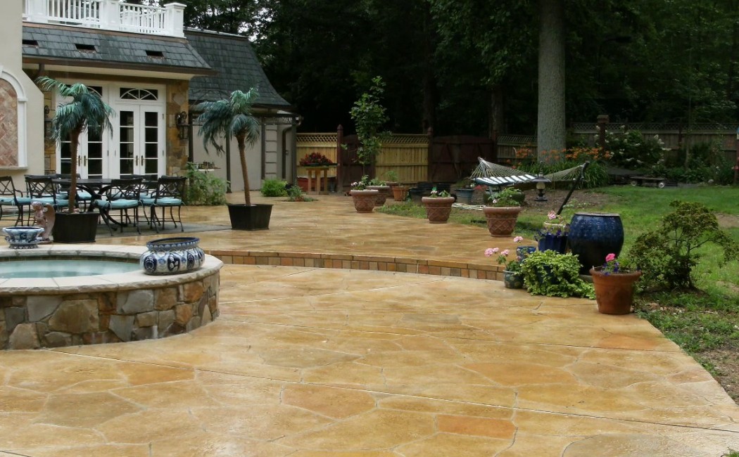 Beautiful backyard patio with stamped flooring, planters, and seating, highlighting premium Decorative Concrete Services for elegant and long-lasting outdoor spaces.