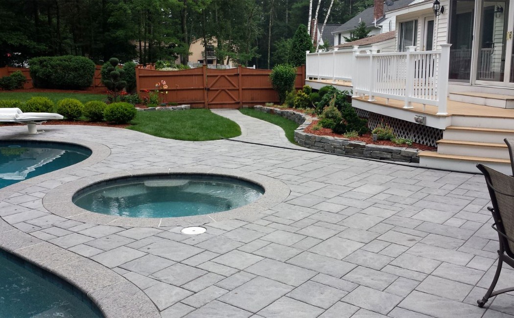 Spacious backyard featuring a paved patio, swimming pool, spa, and deck area designed with professional Hardscape Installation Services for outdoor relaxation.